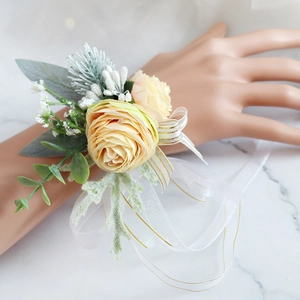 Close-up of champagne rose wrist corsage with white baby's breath and gold-edged ribbon