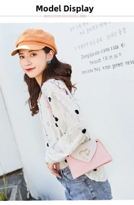 Detail of pink and grey crossbody bag with heart-shaped gold clasp on fashion model