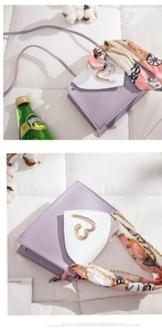 Detail of purple and white crossbody bag with heart buckle and floral silk scarf