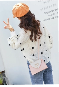 Pink and white color-block crossbody bag with metal heart buckle worn by a model