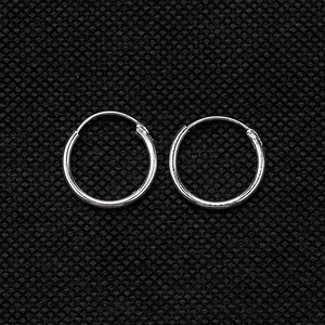 Macro shot of minimalist silver round hoop earrings on a black textured background