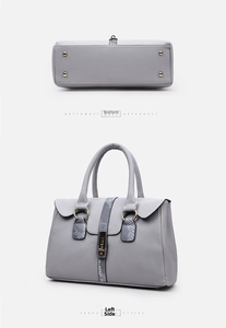 Detail view of grey litchi leather handbag bottom with four golden protective studs
