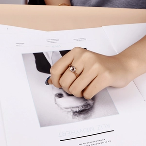 Rose gold hexagonal ring with diamonds shown on model hand against a white magazine