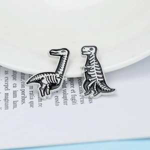 Detailed view of black and white dinosaur skeleton enamel pins on a white plate
