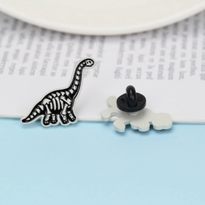 Detailed view of dinosaur skeleton enamel brooch with black and white finish and rubber clutch