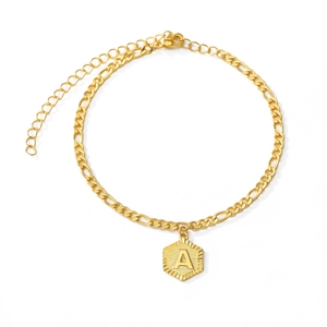 Detail of golden Figaro chain anklet with a brushed hexagonal letter A pendant