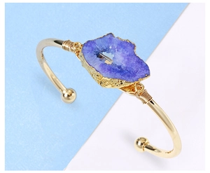 Detailed view of handmade copper wire wrapped purple druzy stone on open gold bracelet