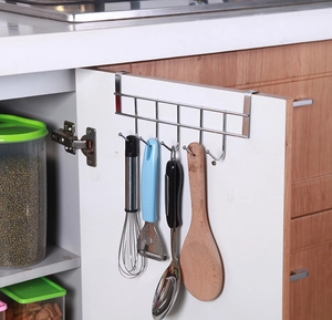 Over-the-door stainless steel hook rack holding kitchen utensils on a cabinet door