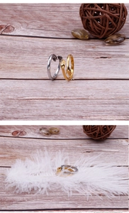 Detailed view of hug hands ring in gold and silver finish resting on a white feather
