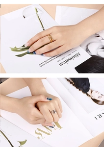 Close-up of minimalist gold and silver hugging hands open rings on a magazine