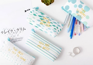 Detail of canvas pencil cases featuring striped and polka dot patterns with gold foil text