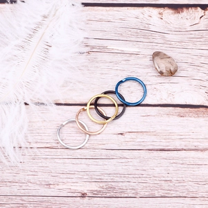Minimalist stainless steel rings in five colors on a natural wooden background