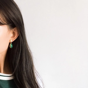 Detailed view of teardrop emerald stone earring on model with sparkling accents