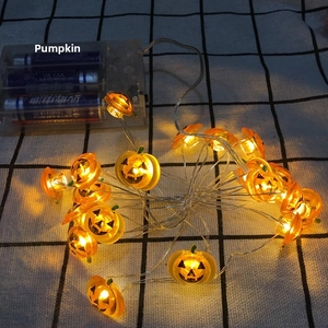 Macro shot of glowing orange pumpkin LED string lights with battery pack controller