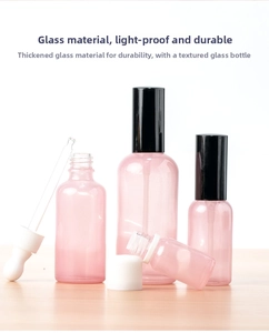 Pink frosted glass spray and dropper bottle set on a light wood surface background