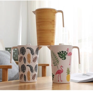 Three bamboo fiber water pitchers with nature prints stacked on a wooden table