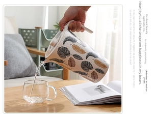 Bamboo fiber pitcher pouring water into a glass with leaf and feather patterns