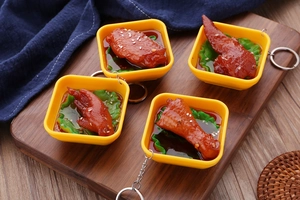 Macro view of four realistic food keychains with glazed chicken wings and metal rings