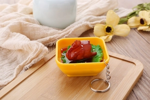 Macro detail of a miniature food bowl keychain with realistic braised meat on a wooden tray