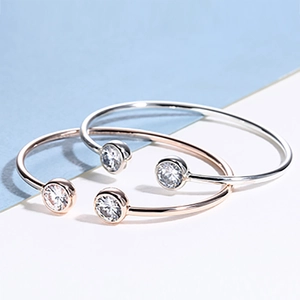Detail of open cuff bracelets in silver and rose gold with bezel-set zircon stones
