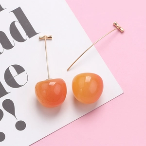 Detail of sweet cherry drop earrings featuring orange gradient resin and long pins