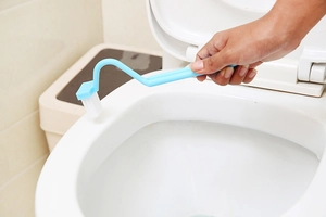 Blue V-shaped toilet brush with long handle cleaning the inner rim of a bathroom bowl
