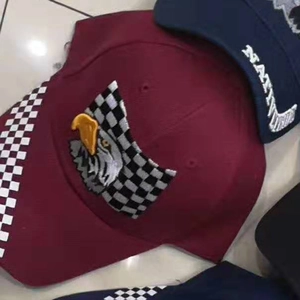 Detail of burgundy and navy baseball caps with eagle embroidery and racing flag patches