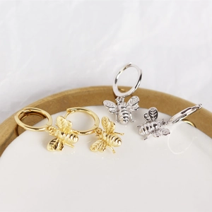 Detailed macro view of S925 sterling silver bee charm earrings in gold and silver finish