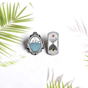 Detailed view of creative enamel pins featuring beach bottle and sun hourglass designs