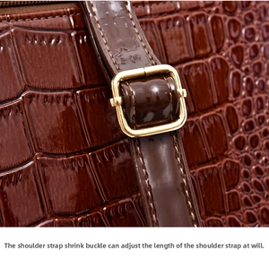 Close-up of adjustable strap buckle on dark brown crocodile pattern leather handbag