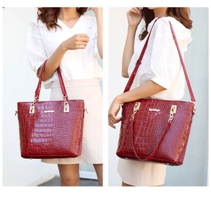 Close-up of wine red crocodile pattern tote bag with polished golden hardware accents