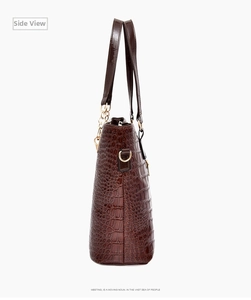 Detail view of the deep brown crocodile embossed tote bag with glossy finish and chain charm