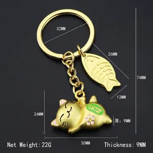 Golden Maneki Neko lucky cat keychain with fish bone charm on a dark background