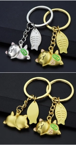 Detailed view of Maneki Neko cat keychains with gold and silver finishes and fish bone charms