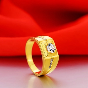 Macro shot of gold plated men's wedding ring with round diamond on red silk