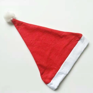 Detailed view of red Christmas hat with white plush trim and pompom on white background