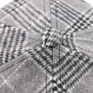 Macro view of black and white plaid tweed hat crown with reinforced fabric button