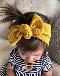 Detail of ginger yellow waffle knit baby headband with bow knot on infant model
