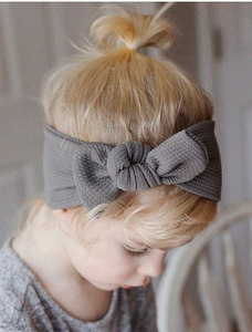 Close-up of grey waffle fabric baby headband with a large bow worn by an infant