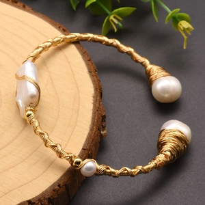 Detail of handcrafted gold wire wrapped bangle featuring white baroque freshwater pearls