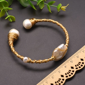 Handmade gold wire-wrapped cuff bracelet featuring four natural baroque freshwater pearls