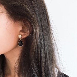 Elegant gold drop earrings with black teardrop stone and crystal pavé on model