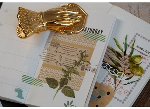 Vintage Victoria style gold hand-shaped metal paper clip on a creative floral notebook