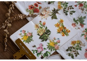 Close-up of vintage PET floral stickers with roses and peonies on a grid notebook
