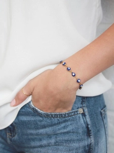 Close-up of golden Evil Eye charm bracelet worn by model for a casual daily lifestyle look