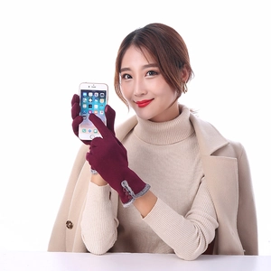 Close-up of wine red gloves with faux fur trim and buttons showing touch screen use