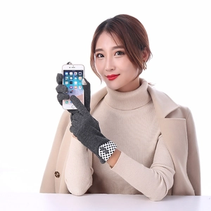 Close-up of dark grey touchscreen knit gloves featuring plaid cuff and button detail