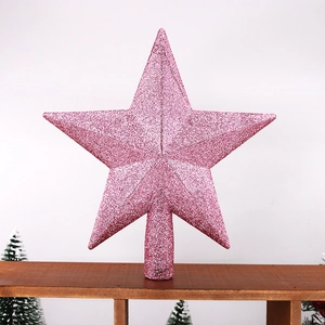 Pink glitter star tree topper decoration on a wooden shelf with mini Christmas trees
