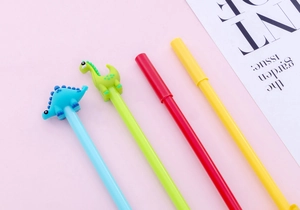 Close-up of cute dinosaur gel pens in four colors on a soft pink decorative background