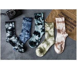 Détail de chaussettes en coton tie-dye en cinq couleurs avec bords-côtes sur fond industriel